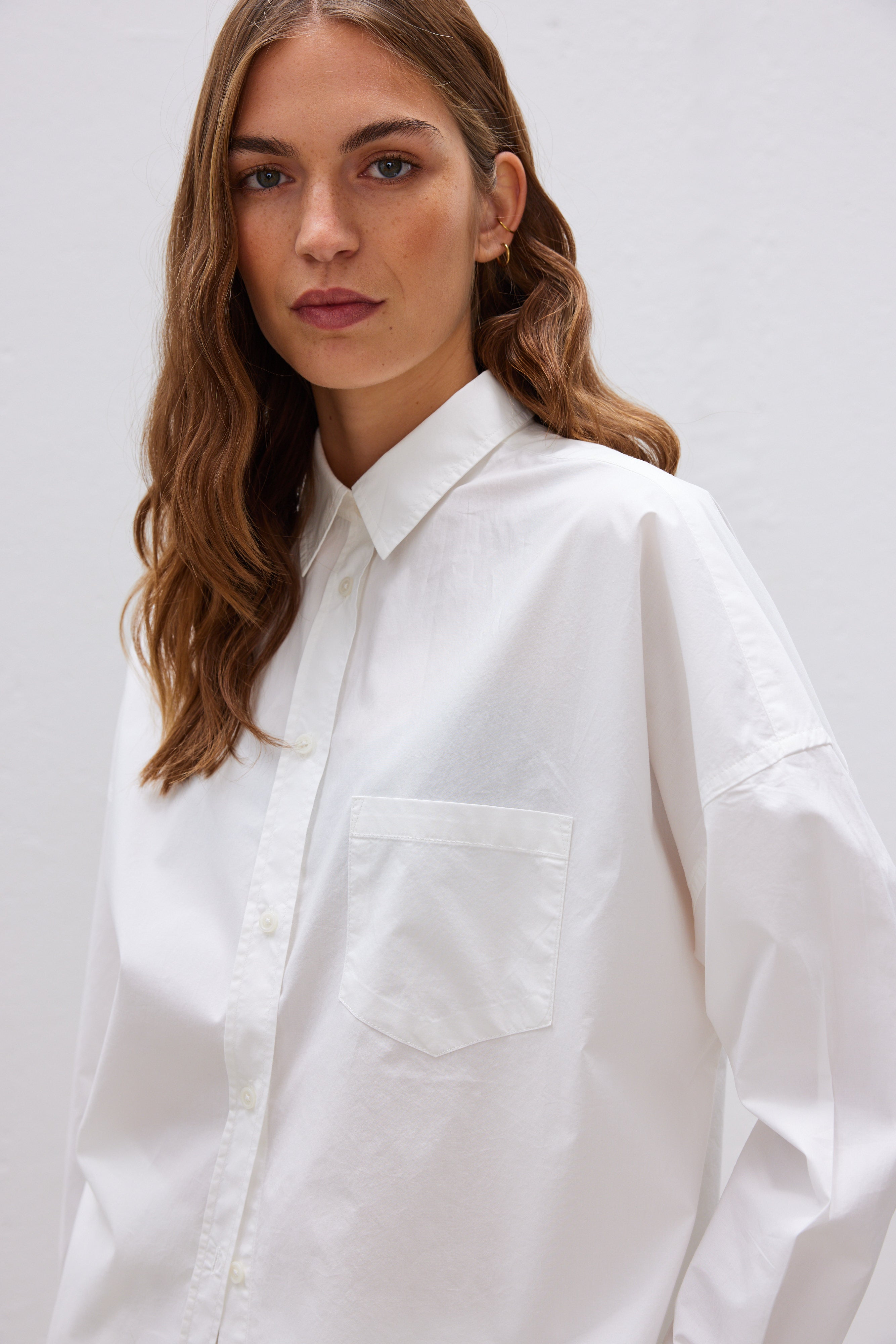 White cotton shirt front view showing relaxed fit and chest pocket detail