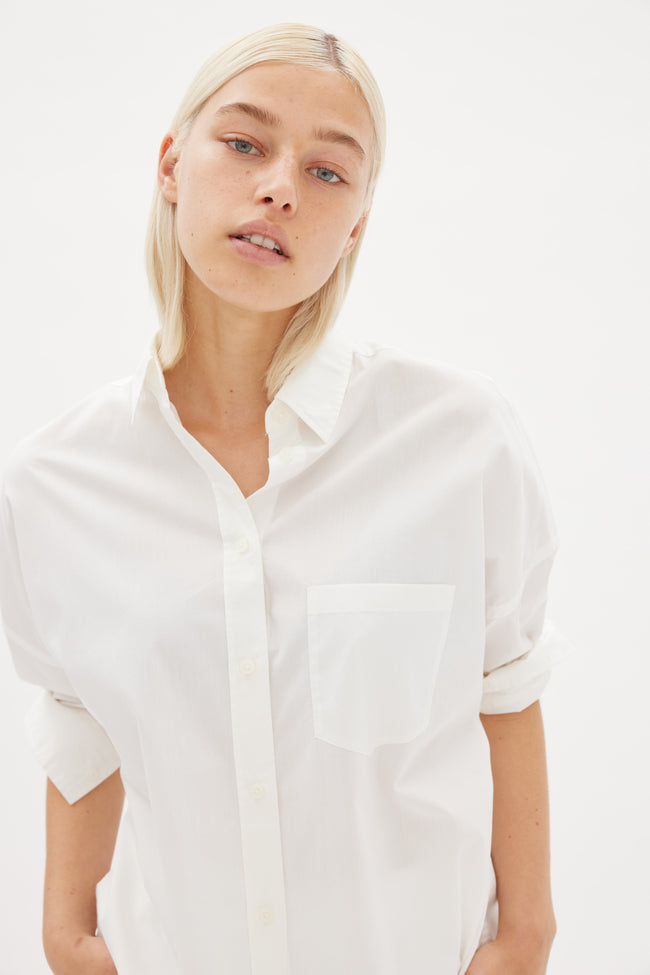 White cotton shirt front view showing relaxed fit and chest pocket detail
