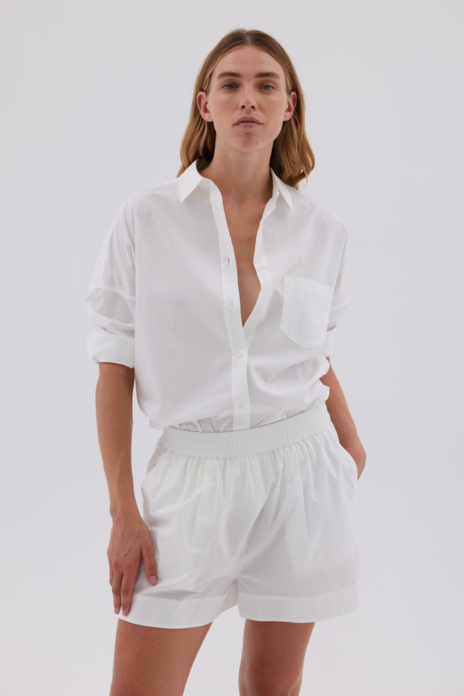 Woman wearing white cotton button-up shirt with relaxed fit and drop shoulders